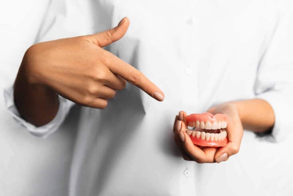How to Clean Dentures 1 Dentist pointing to a denture held in the hand