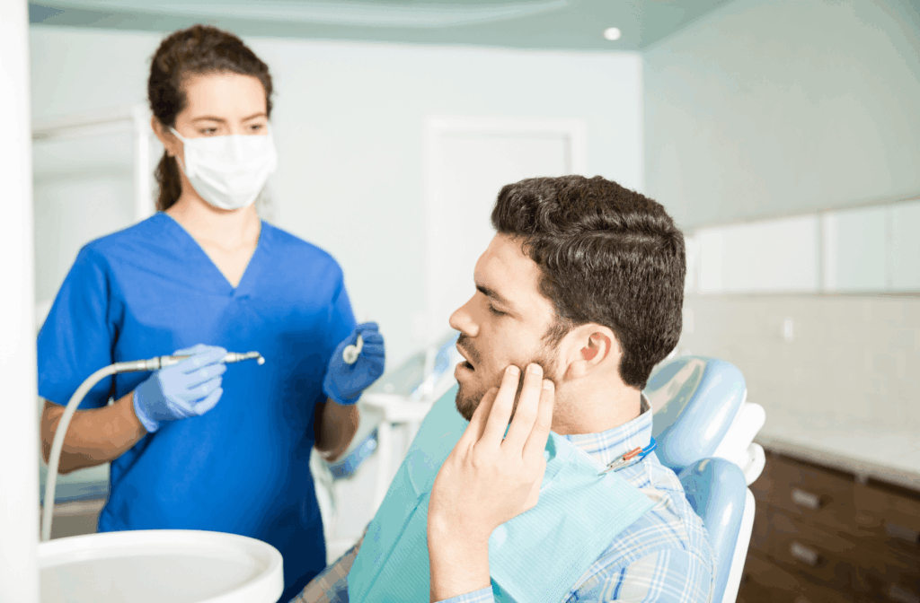 Can a Toothache Cause a Headache? 1 Patient holding his jaw in pain while talking to a dentist